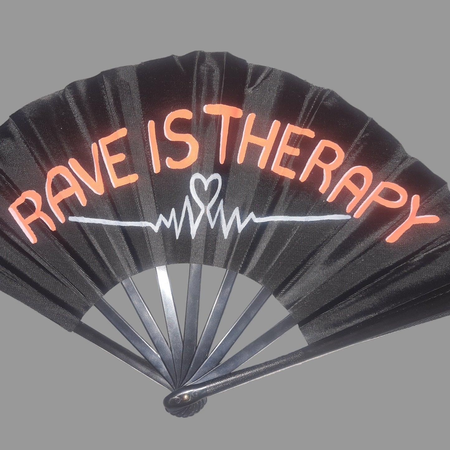 Rave Is Therapt UV Fan, black handpainted with orange bubble writing and white heartbeat line, UV reactive for festivals and raves