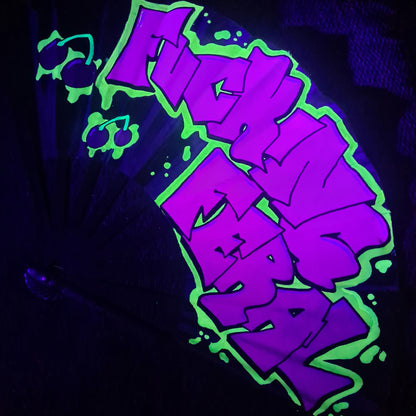 Fucking Feral UV Fan, black handpainted with purple graffiti lettering, yellow outline and red cherries, UV reactive for festivals and raves