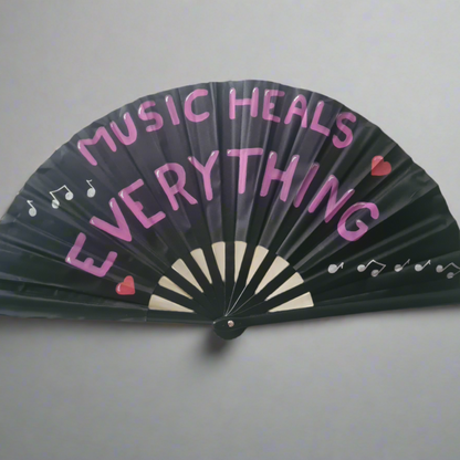 Music Heals Everything UV Fan, black handpainted with purple  lettering, white music notes and red hearts, UV reactive for festivals and raves
