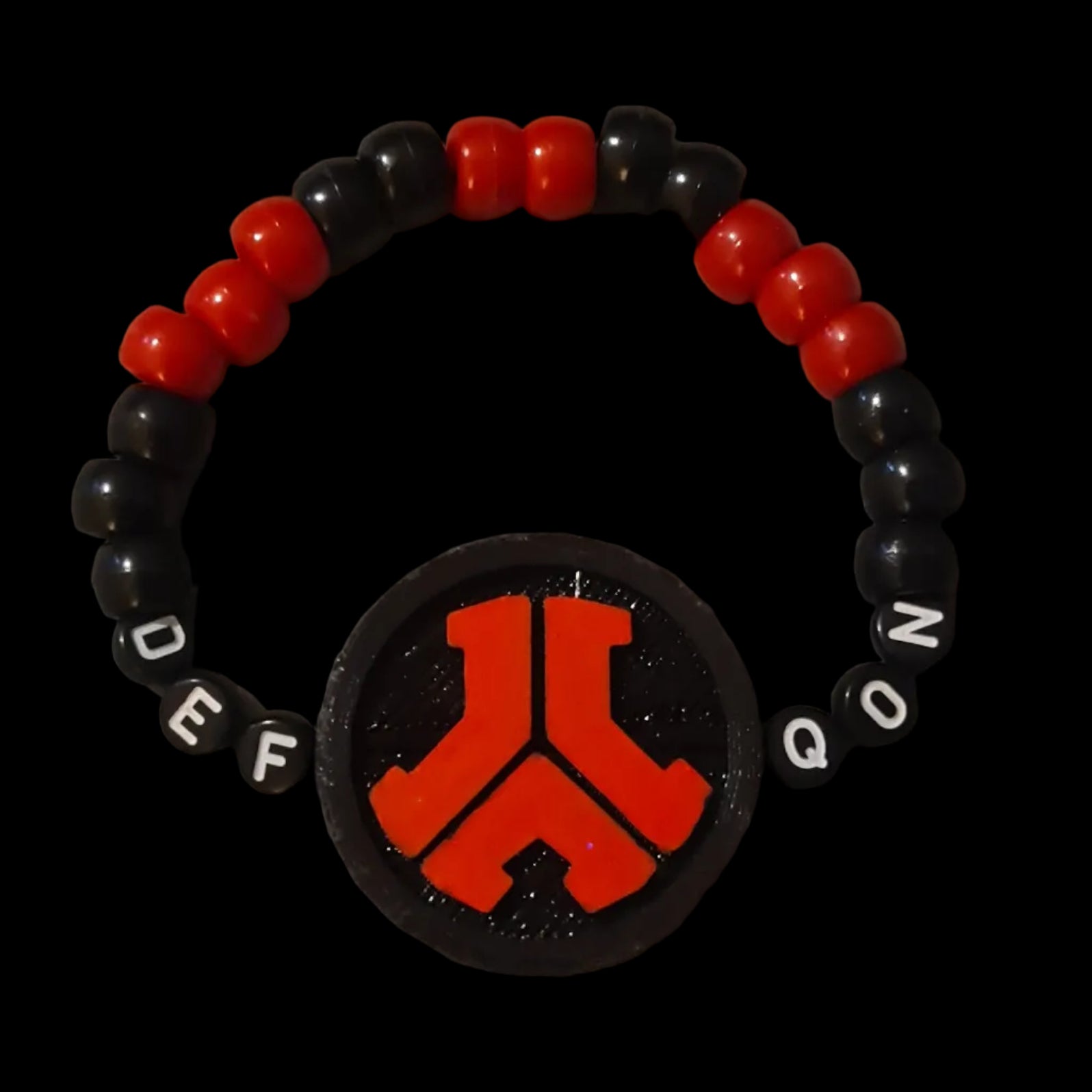 Black and red beaded bracelet with a central emblem on a black background