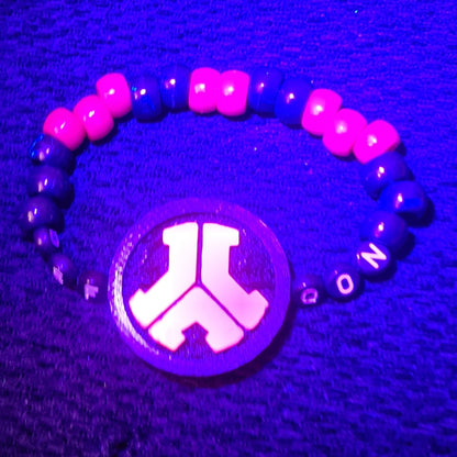 Glowing bracelet with pink and blue beads on a dark purple background