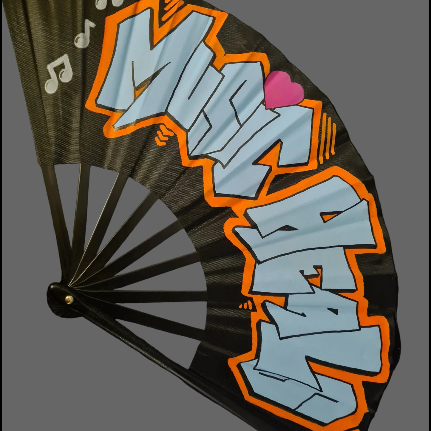 Music Heals UV Fan, black handpainted with blue graffiti lettering, orange outline and white music notes, UV reactive for festivals and raves
