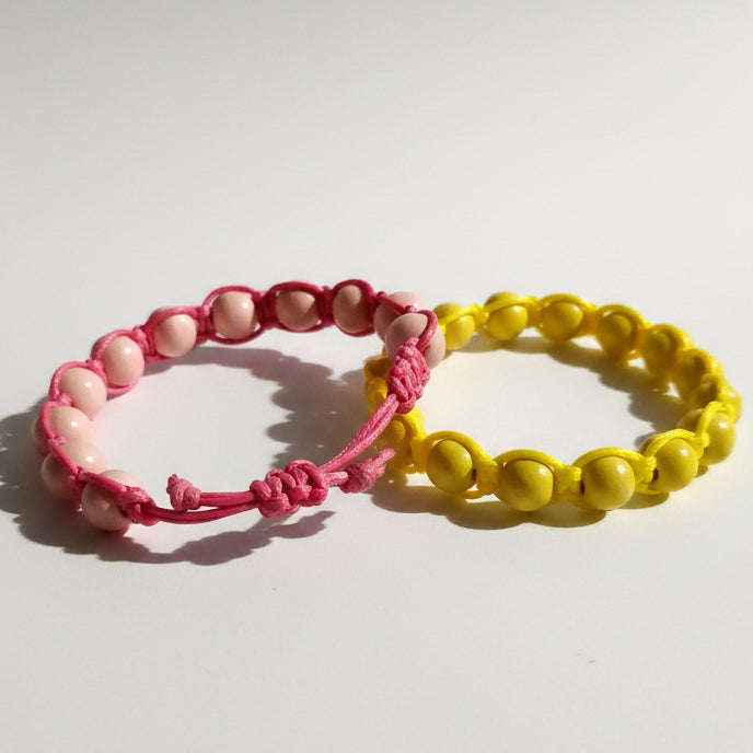Two beaded bracelets, one pink and one yellow, on a white background