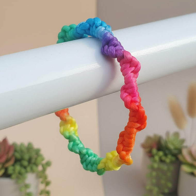 Colorful braided bracelet on a white surface with a blurred background