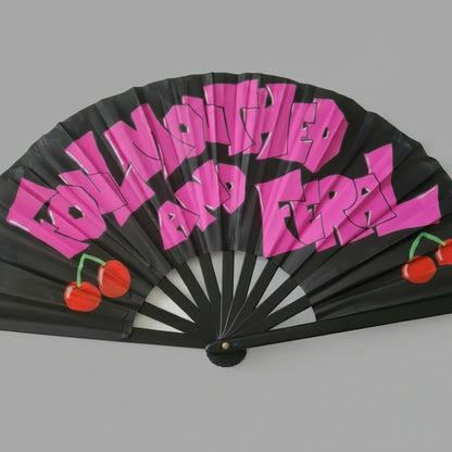 Black fan with pink text and red cherries on a gray background